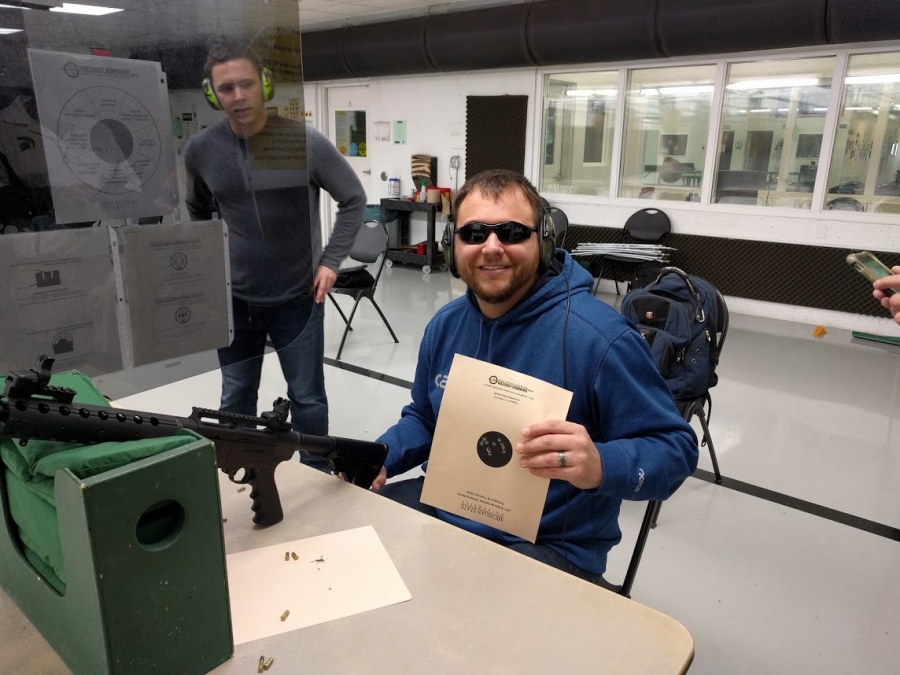 Nick V., person with visual impairment, poses with shooting target.