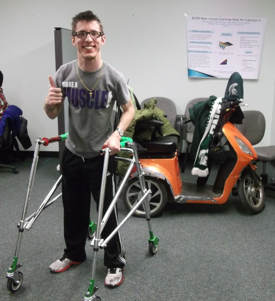 Student standing with athletic walker, smiling and giving a thumbs up.