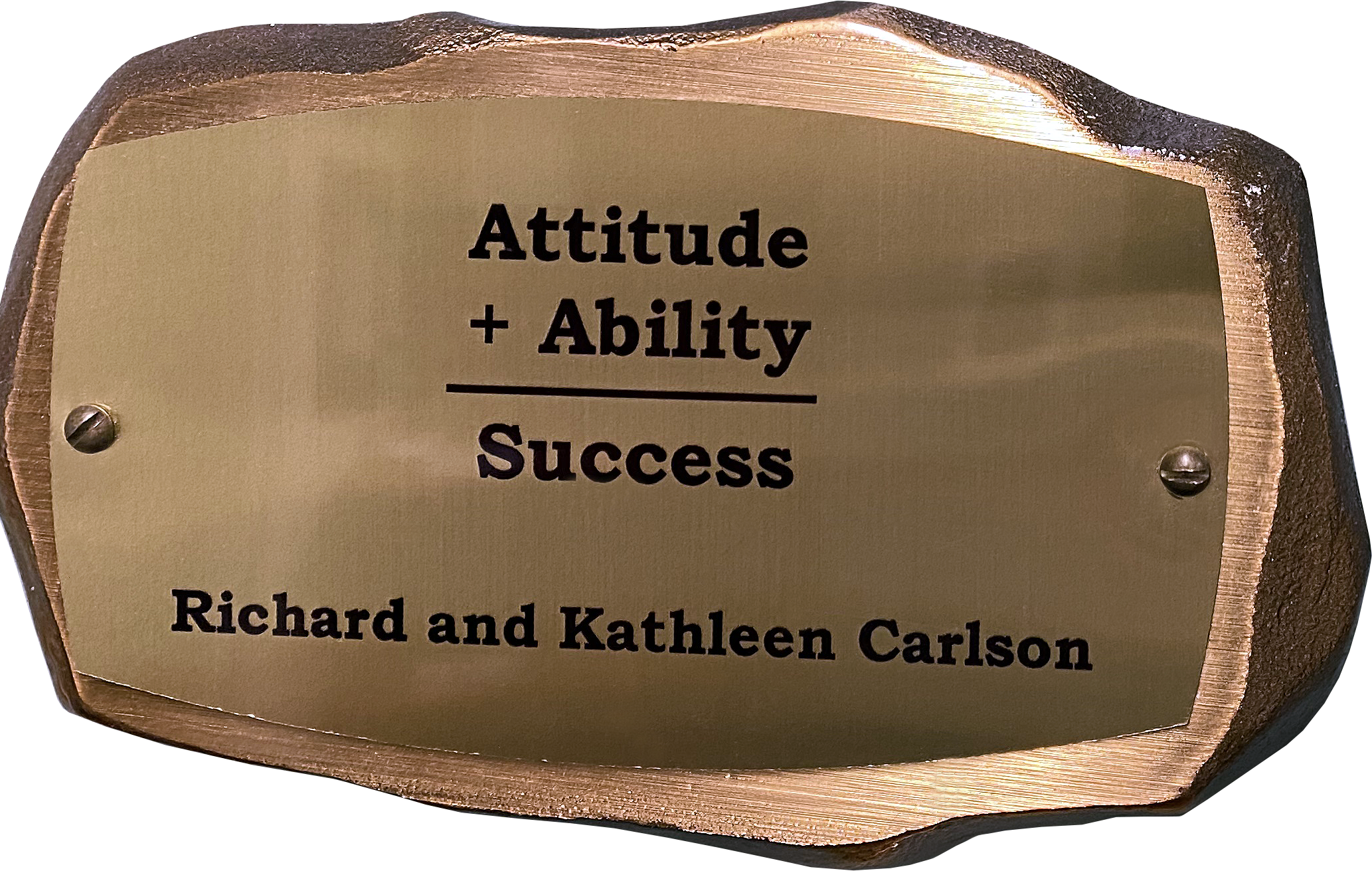 Inscribed bronze plaque in the shape of a rock with text on it reading: Attitude + Ability = Success. Richard and Kathleen Carlson
