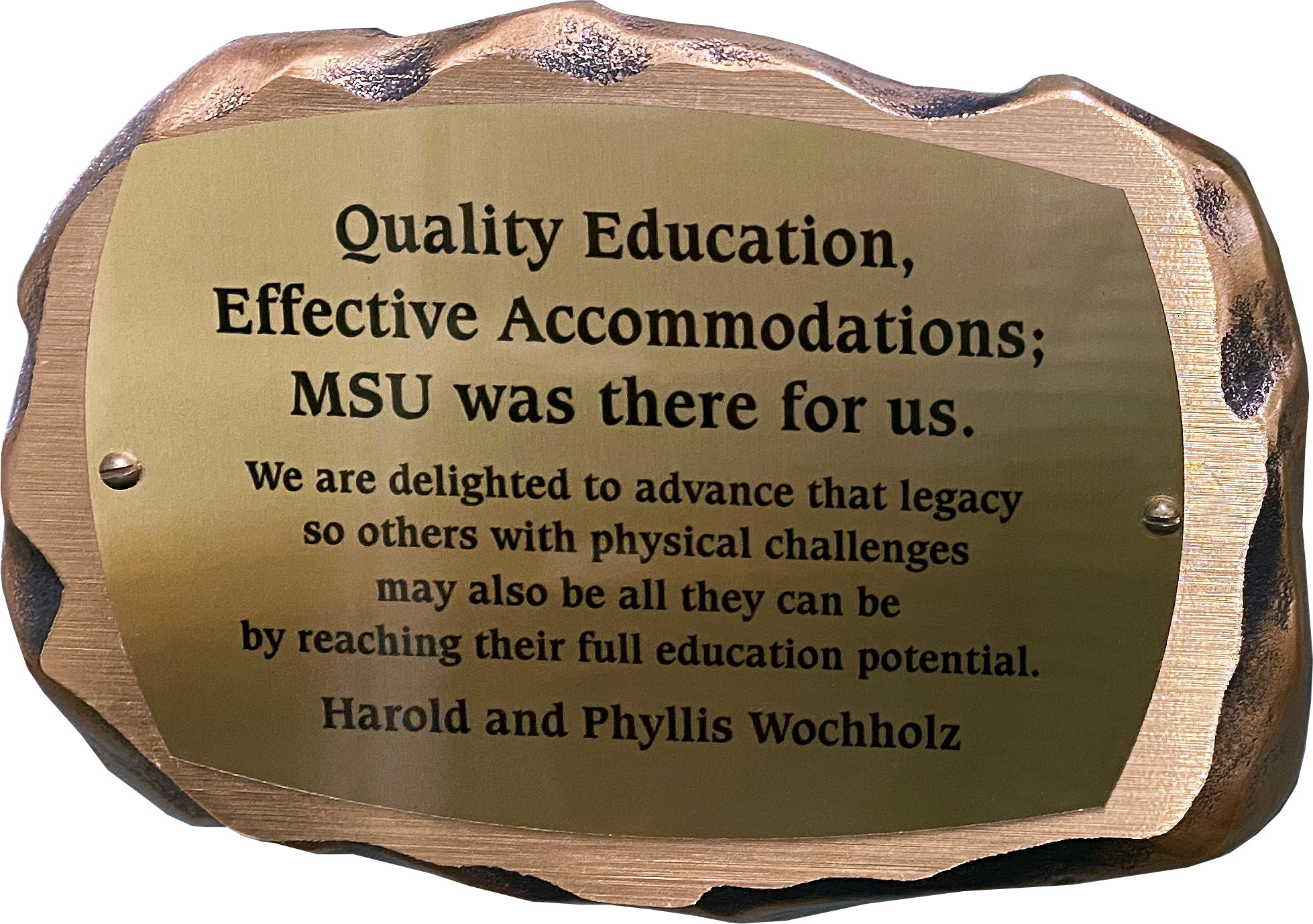 Inscribed bronze plaque in the shape of a rock with text on it reading: "Quality Education, Effective Accommodations; MSU was there for us. We are delighted to advance that legacy so others with physical challenges may also be all they can be by reaching their full potential. Harold and Phyllis Wochholz"