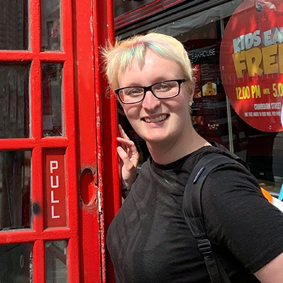 Photo of Courtney standing beside red telephone booth in London