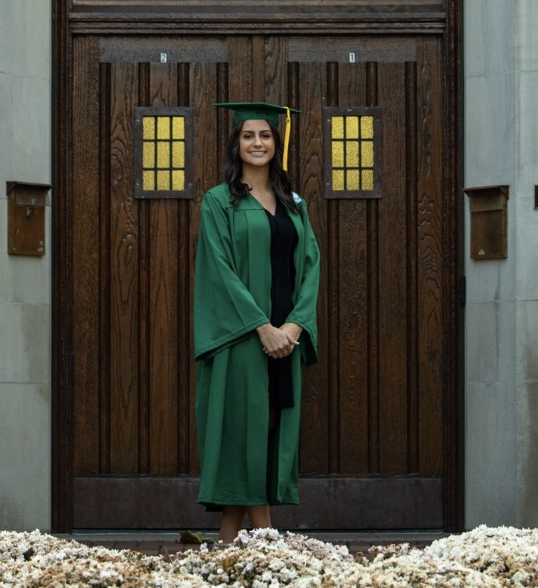 Pictured is Abby Cortis, standing in front o brown double doors, accompanied by flowers.