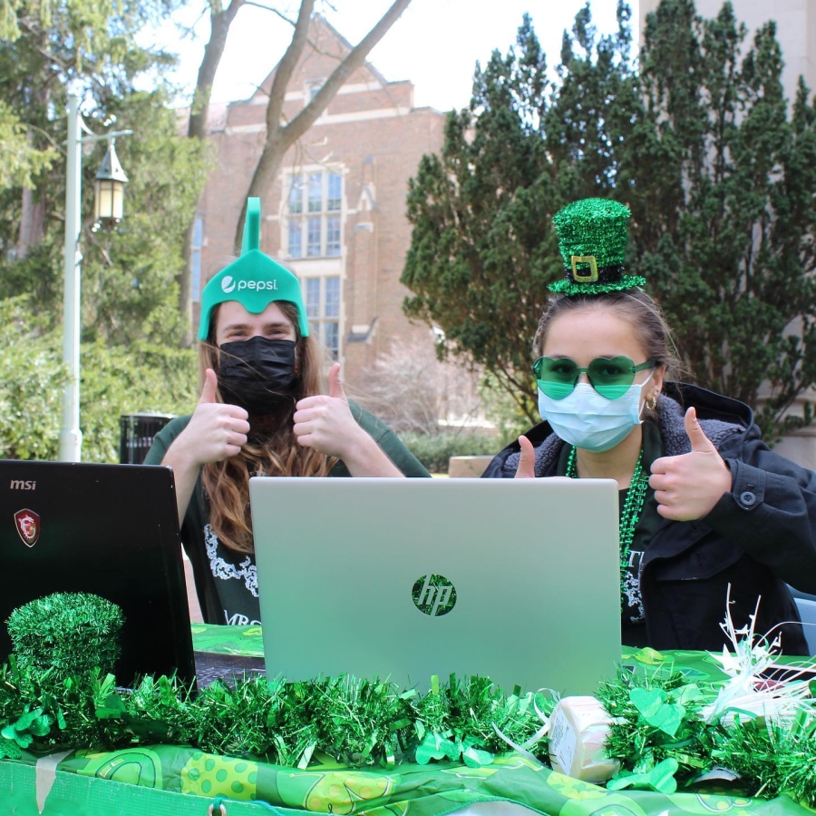 Pictured are Tower Guard e-board Run chair members, masked Madeline and Jackson, at the Shamrock 5K table under Beaumont Tower