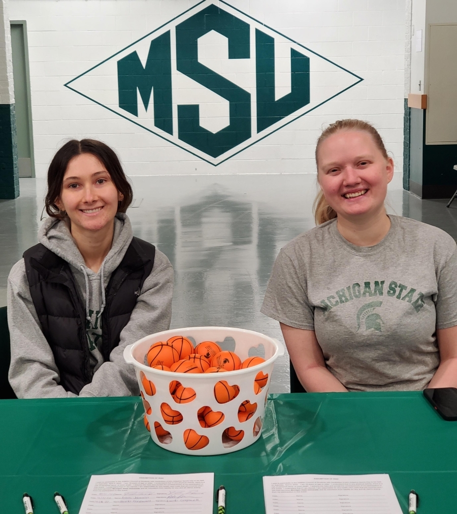 Megan with Emma Bush at a Council for Students with Disabilities event; they are sitting at a registration table.