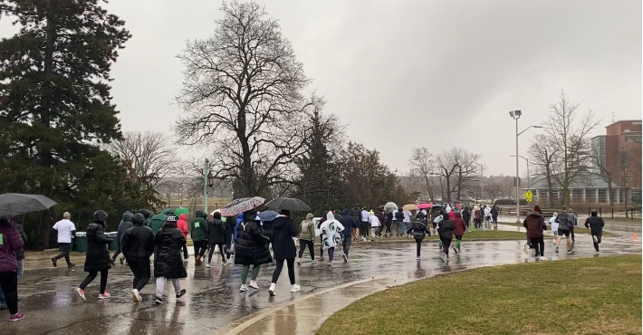 A group of runners run between MSU Auditorium and the Rock on a dreary, rainy morning.