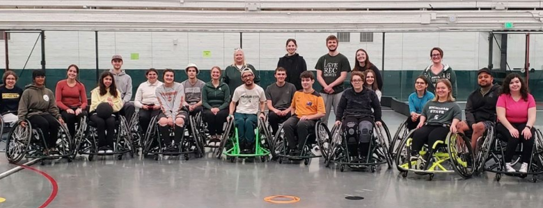 Tower Guard members and Adaptive Sports members join together smiling at the camera on Adaptive Sports Day while in wheelchairs.