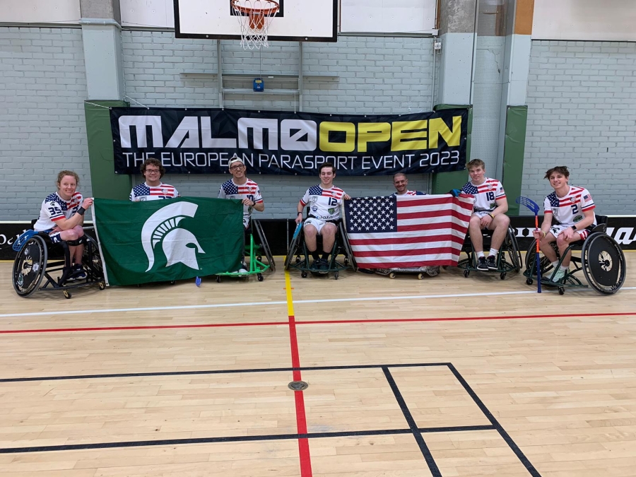 Wheelchair Floorball Teammates holding the USA and MSU flags