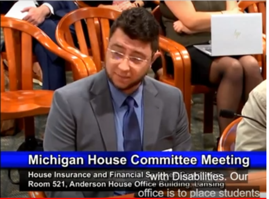 Tyler Smeltekop wearing a gray suit and tie testifies at the MI House of Representatives Hearing on House Bills 4944 and 4963