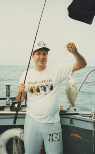 Photo of Philip Trosko fishing. He is holding a fish and is on a boat.
