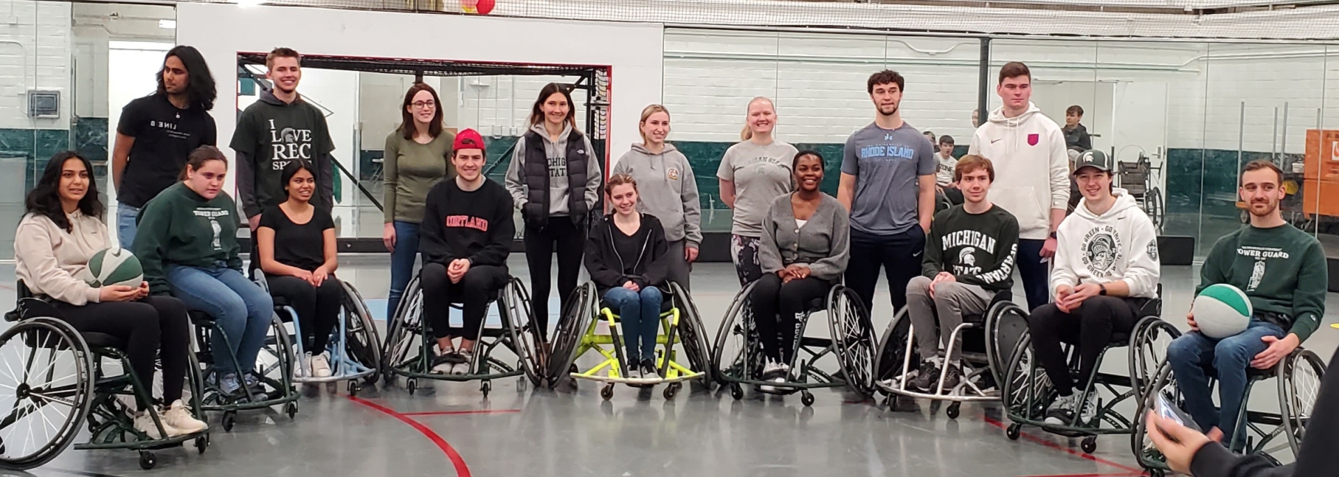 A group shot of some of the attendees smiling. Some are standing and some are in wheelchairs. 