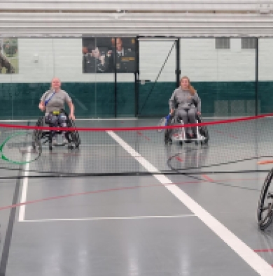 An action shot of students in wheelchairs playing tennis