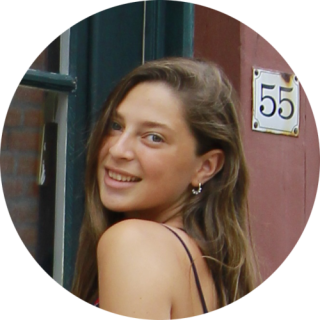 Photo of Alisar Alabdullah, young woman with long dark hair smiling as she looks back over her shoulder at the camera.