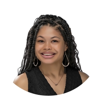 Photo of DuJour Johnson – A young, smiling African-American woman with mid-back length braids tucked behind her shoulders. She is wearing a black v-neck dress, a small gold pendant necklace, and large, gold teardrop earrings.