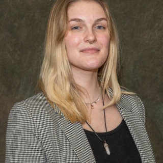 Image of Paige Lawson - They are white with medium length blonde hair. She is wearing a black and white blazer over a black shirt.